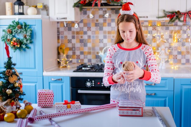 Una niña en pijama de navidad empacando regalos de navidad