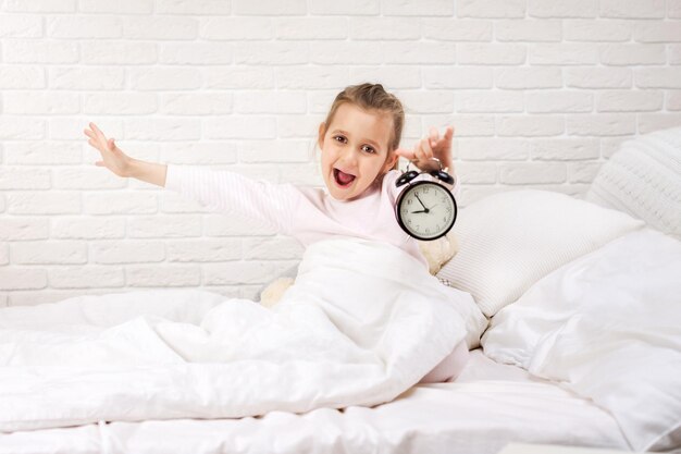 Foto niña en pijama con reloj