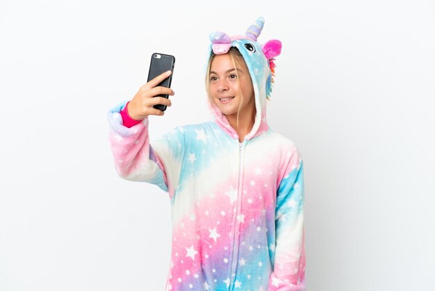 Niña con pijama de unicornio aislado sobre fondo blanco haciendo un selfie