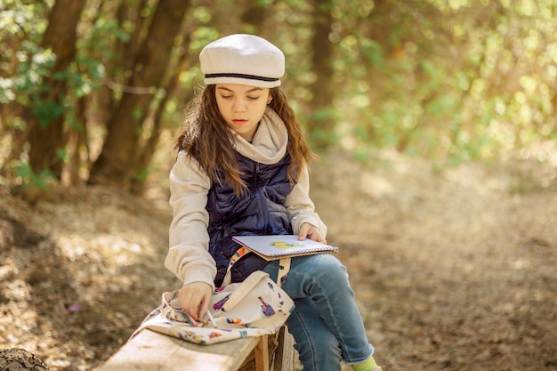 Niña pinta al aire libre en primavera floreciente parque de cuento de hadas Dibujos infantiles Niño creativo