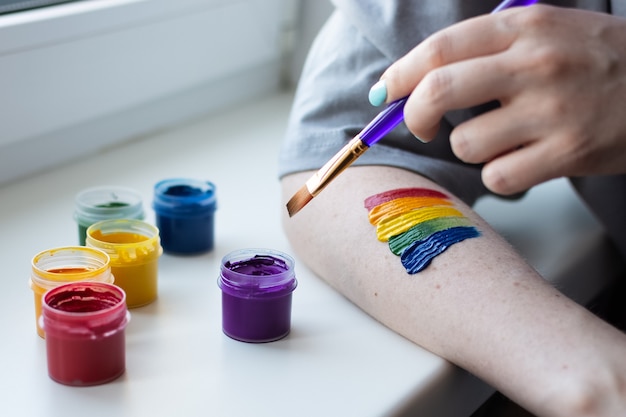 Una niña pinta un arco iris en su mano con los colores de la comunidad lgbt