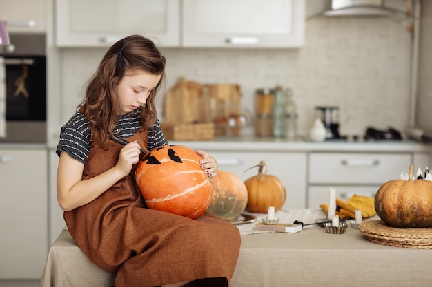 Niña pinta una calabaza para la preparación de Halloween para Halloween