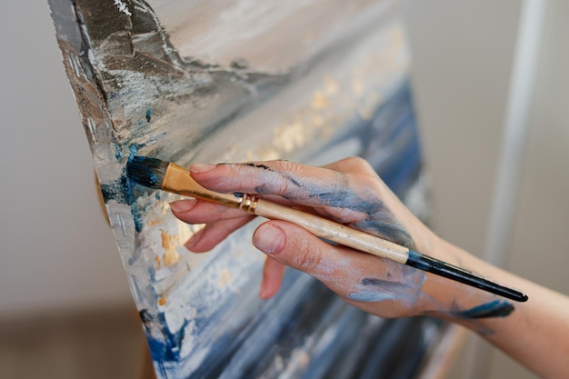 La niña pinta un cuadro con pinturas acrílicas y un pincel. El proceso de creación de una imagen.