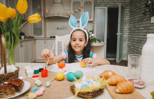 Niña pinta huevos de Pascua Familia feliz se prepara para Pascua Linda niña con orejas de conejo el día de Pascua