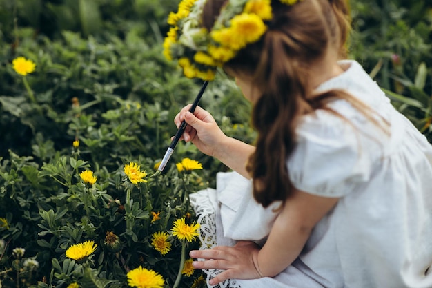 niña pinta un pincel de flores amarillas en el campo