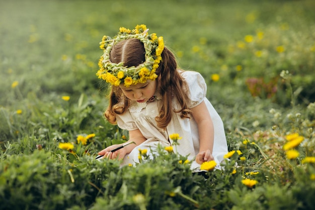 niña pinta con un pincel flores en el campo