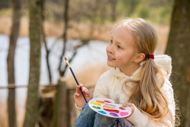 Niña pinta en la primavera sobre la naturaleza