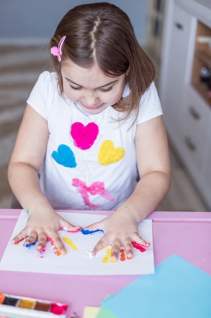 Foto niña pintando con sus manos y dedos en casa