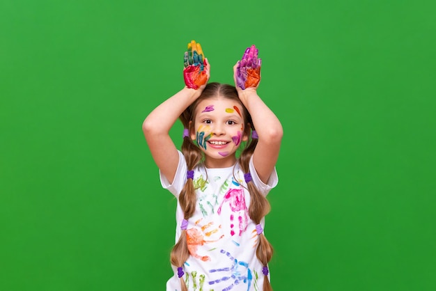 Una niña con pintura, un niño se ha manchado las manos y la cara con pintura y está feliz Una niña con las manos manchadas con pintura en un fondo aislado