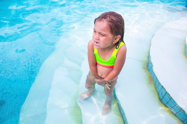 Niña en la piscina en el frío temblando