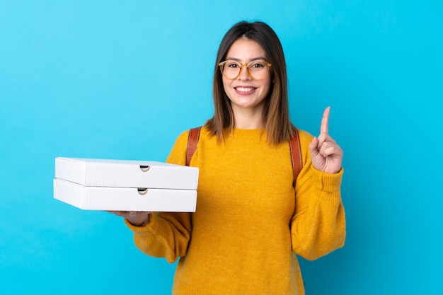 Niña con pizzas sobre pared azul