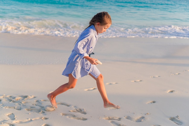 Niña en la playa blanca al atardecer