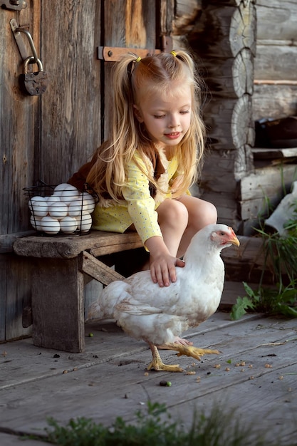 Niña con un pollo blanco en el campo Agricultura de subsistencia y concepto de comida orgánica