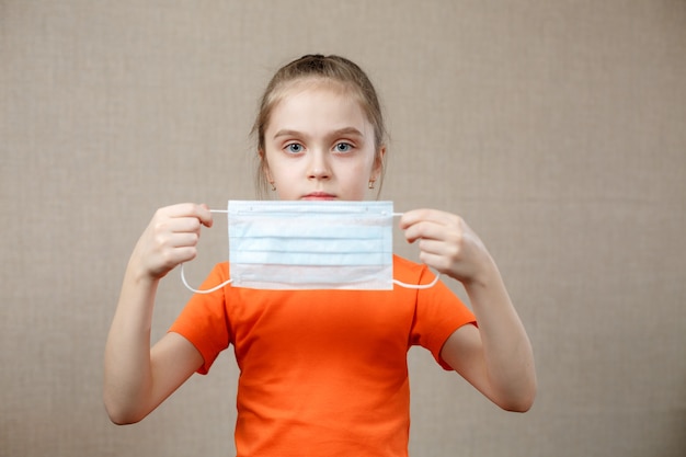 Foto la niña se pondrá una mascarilla médica protectora. epidemia de coronavirus 2019.