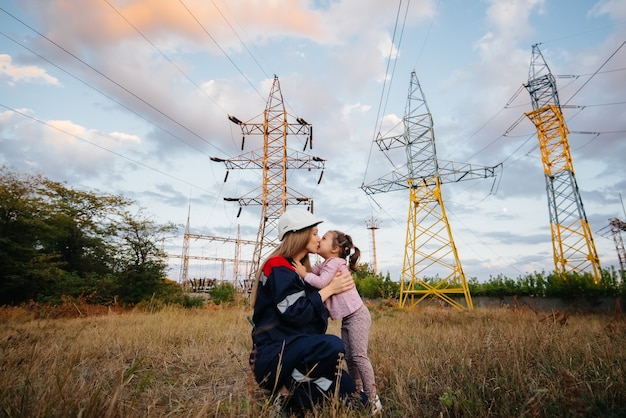 Una niña le pone un casco a su madre a un trabajador de ingeniería. Preocupación por las generaciones futuras y el medio ambiente. Energía.