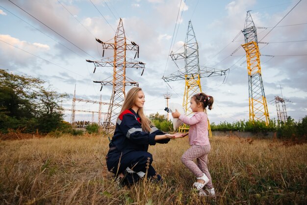 Una niña le pone un casco a su madre a un trabajador de ingeniería. Preocupación por las generaciones futuras y el medio ambiente. Energía.