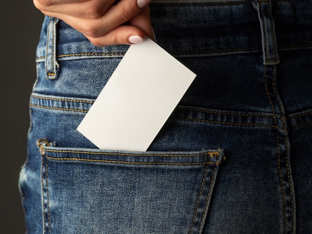 La niña pone la tarjeta de presentación en el bolsillo trasero de sus jeans. Copie el espacio, concepto de negocio