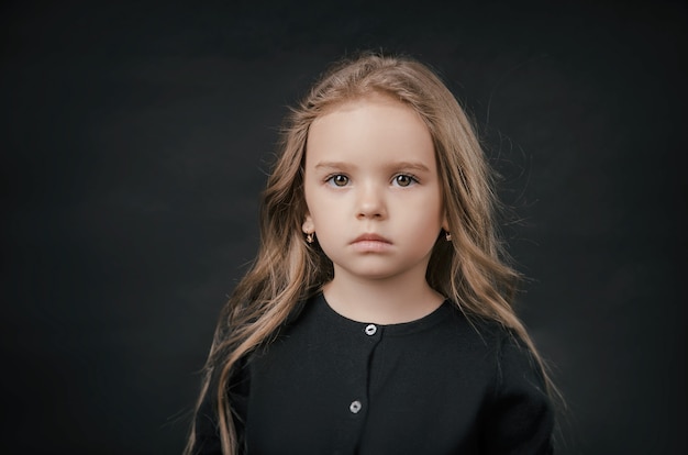 Niña posando perfectamente en el estudio sobre un fondo negro