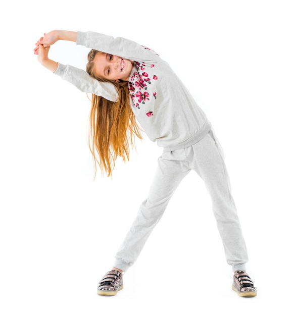 Niña positiva haciendo curvas laterales de yoga aisladas sobre fondo blanco