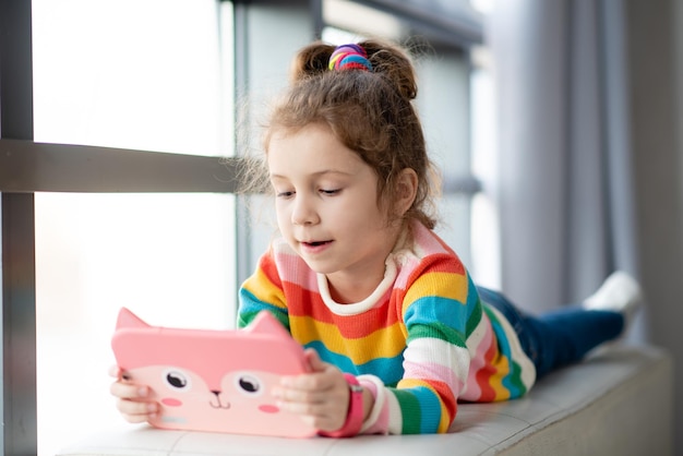 Niña positiva sosteniendo una tableta en sus manos Publicidad nueva aplicación educativa de gadget