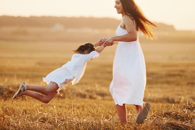 Una niña positiva con su madre tiene un fin de semana al aire libre en el campo de verano juntos