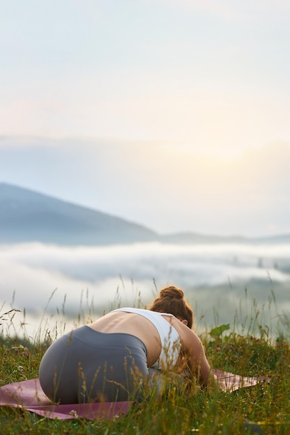 Niña practicando yoga en las montañas