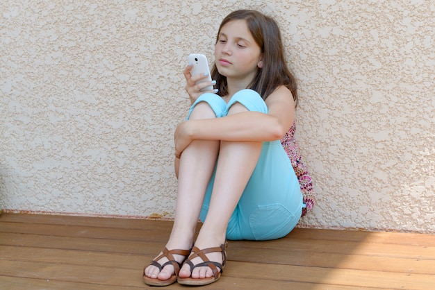 Niña pre adolescente enviando mensajes de texto en el teléfono móvil