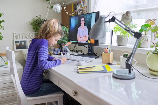 Niña preadolescente aprendiendo matemáticas en línea usando la computadora de casa