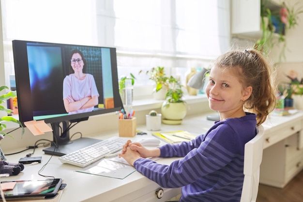 Niña preadolescente aprendiendo matemáticas en línea usando la computadora de casa