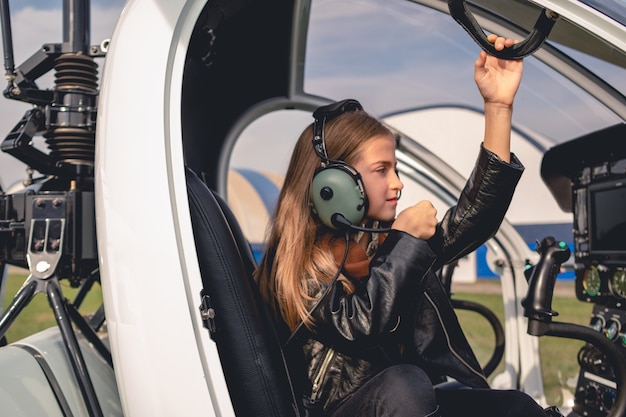 Niña preadolescente enfocada en auriculares piloto sentado en la cabina del helicóptero