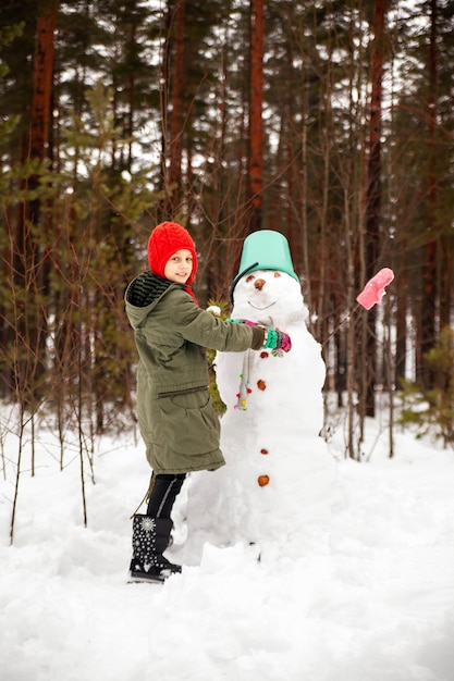 Niña preadolescente en invierno para esculpir un muñeco de nieve