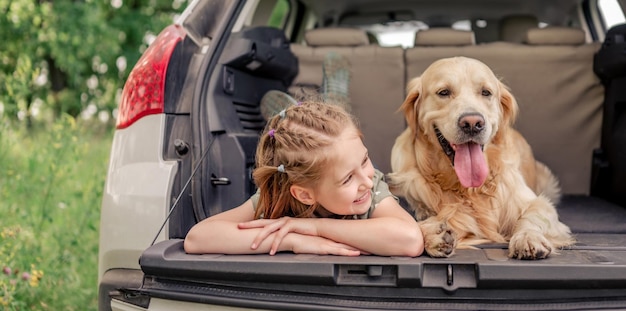 Niña preadolescente con perro golden retriever en el auto