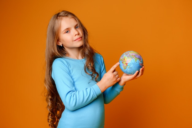 Foto niña preadolescente sosteniendo un globo terráqueo