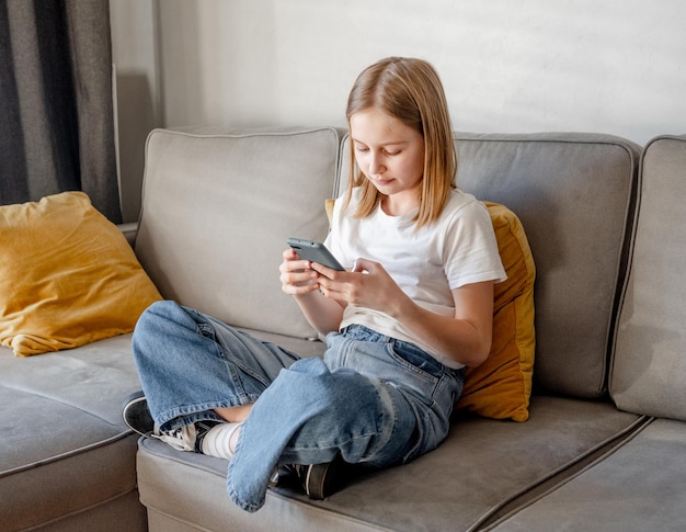 Niña preadolescente con teléfono inteligente en casa