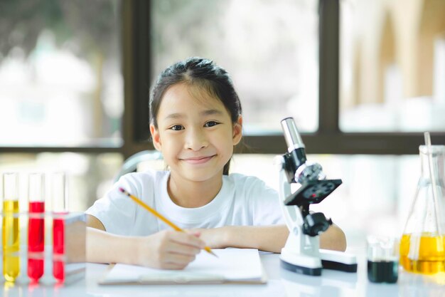 Niña preescolar está interesada en la lección de laboratorio tomando notas en el libro para su estudio