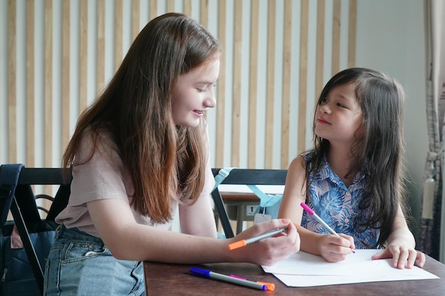 Niña preescolar Kid dibujo con lápiz de color sobre papel blanco sobre la mesa en el aula con amigos