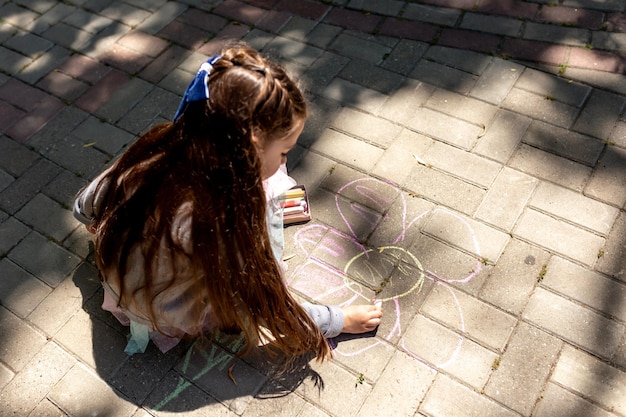 Niña preescolar pintando con tizas de colores Actividad creativa de los niños al aire libre en verano