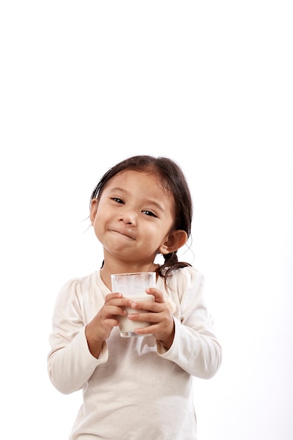 Niña preescolar sosteniendo un vaso con leche