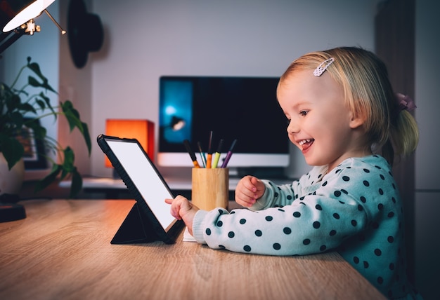 Niña preescolar con tablet pc en la noche en casa