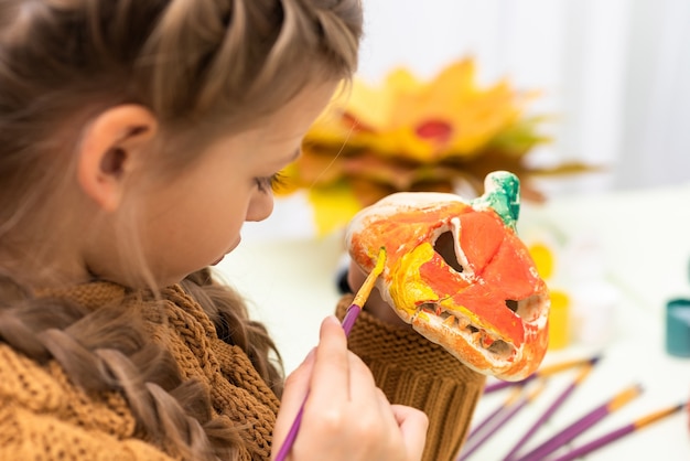 niña prepara una calabaza para la fiesta de Halloween.