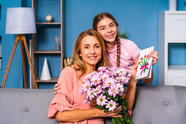 Niña presentando flores a su mamá en casa, momentos felices de la vida doméstica