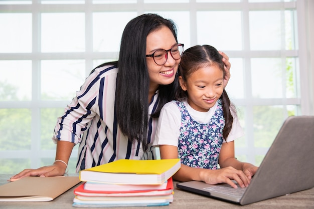 Niña de primaria estudiando computador con maestra