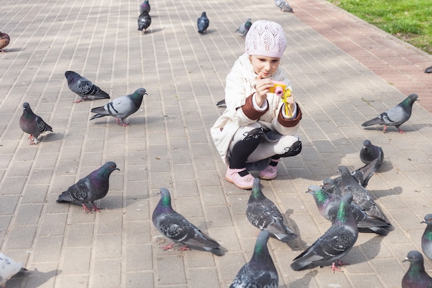 Una niña en la primavera en el parque fotografía palomas con una cámara para niños