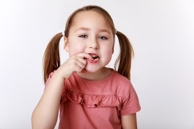Foto niña con el primer diente de leche oscilante