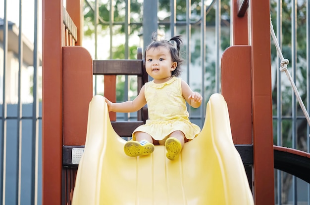 La niña del primer juega un resbalador en el fondo del patio