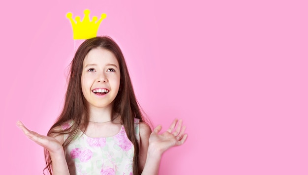 Niña princesa, corona, aislada sobre fondo rosa. Los niños usan el símbolo de la corona de oro de la princesa. Dama princesita. Chica usa corona fondo rosa. Copie el espacio.