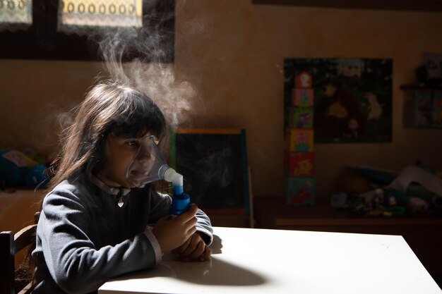 Niña con problemas de asma haciendo inhalación con máscara en la cara