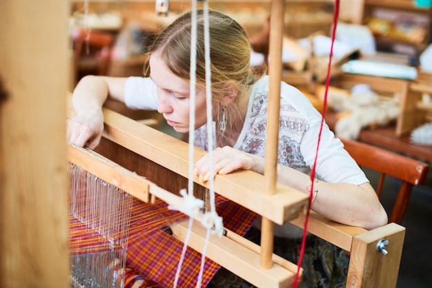 La niña en el proceso de producción de textiles está hecha a mano en un telar.