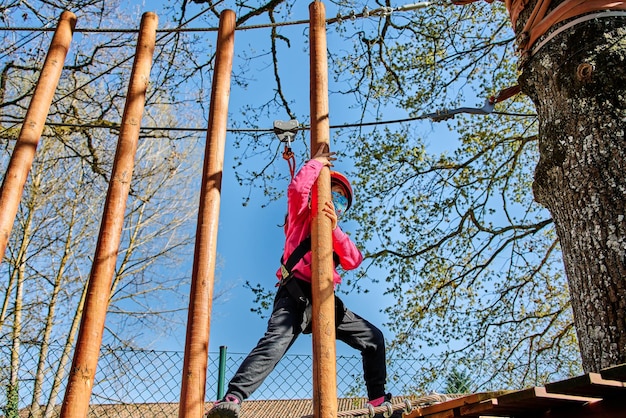 Foto niña con protecciones practicando escalar entre árboles con cuerdas y redes