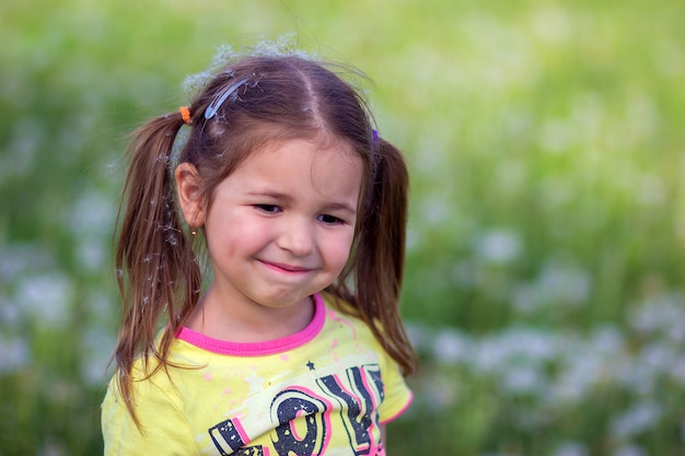 La niña en una prroda con fuzz de dientes de león en la cabeza